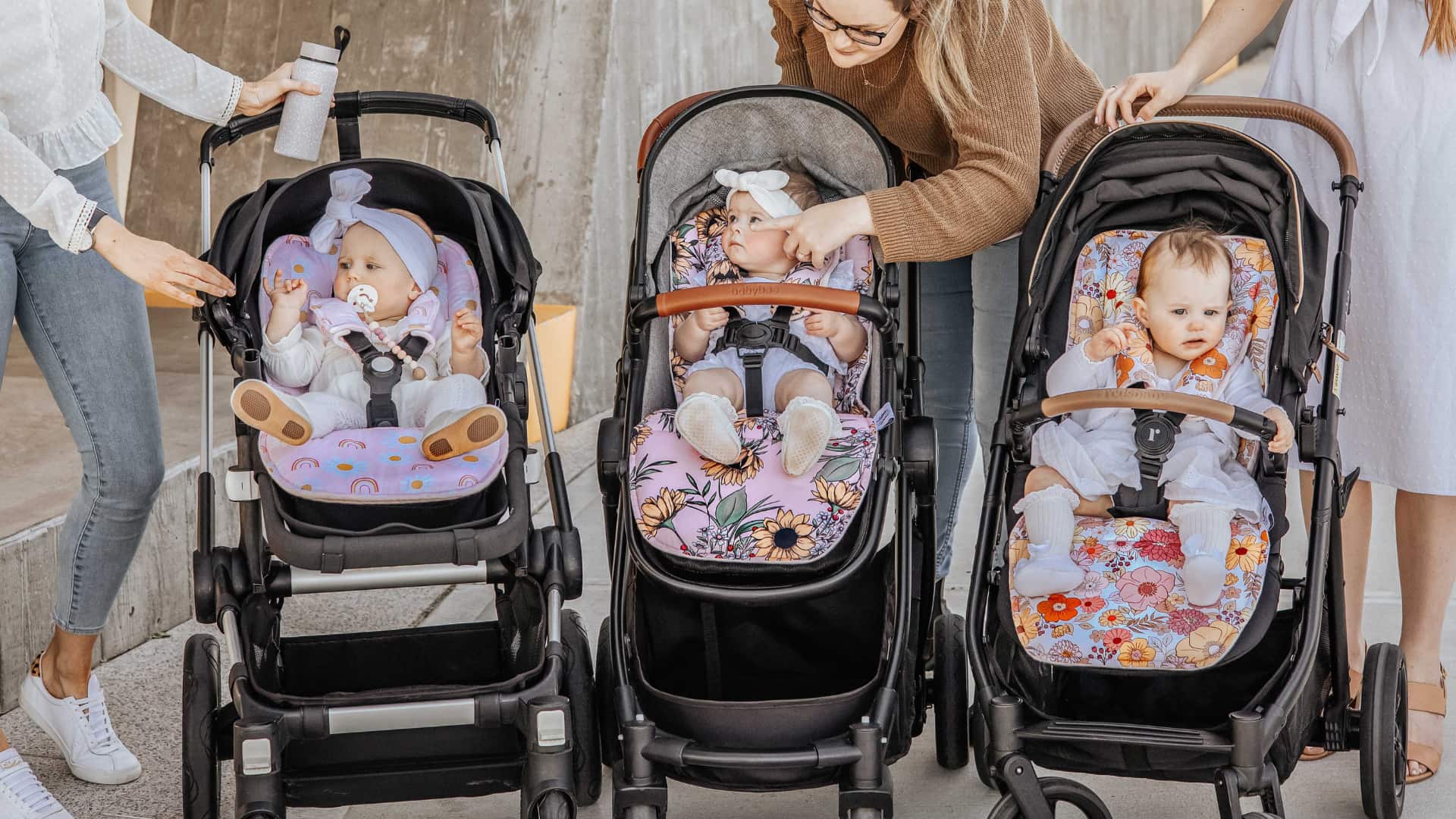Three babies seated in strollers with patterned stroller liners, highlighting comfort, fit, and stylish designs for everyday use.
