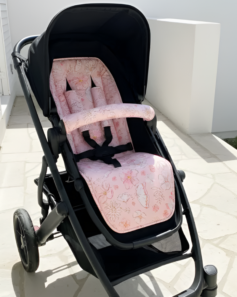 Black stroller with a pink floral seat cover on a light background