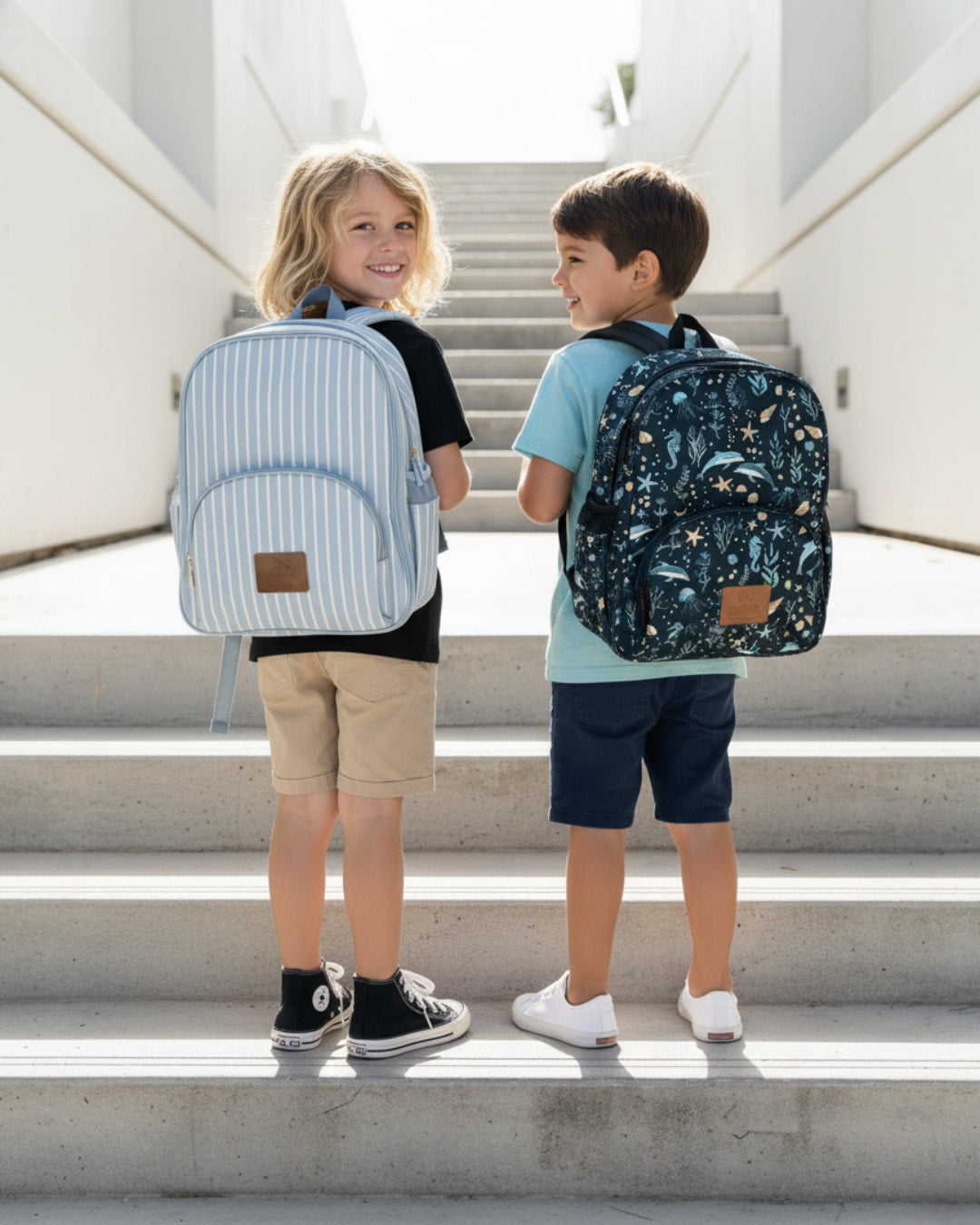Two children standing on a staircase wearing backpacks.