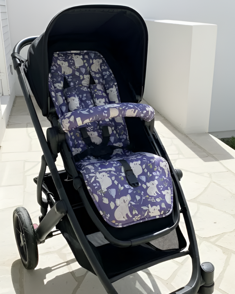 Black stroller with purple and gray patterned seat cover on a white floor.