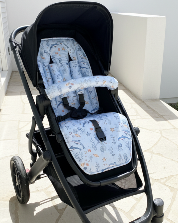 Black stroller with blue floral seat covers on a light-colored floor.