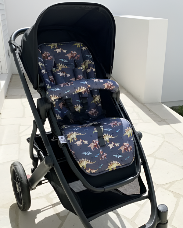 Black stroller with dinosaur-patterned cushions on a white floor.