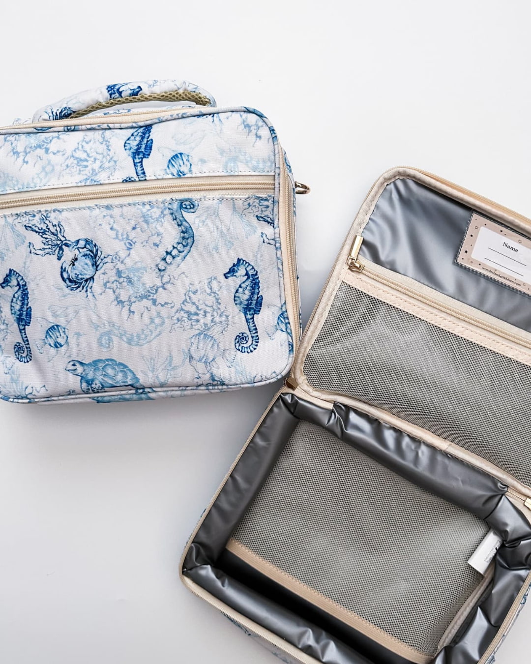 Insulated lunch bag open showing blue ocean print, water-resistant material, internal mesh pockets, and name card for organized meals.