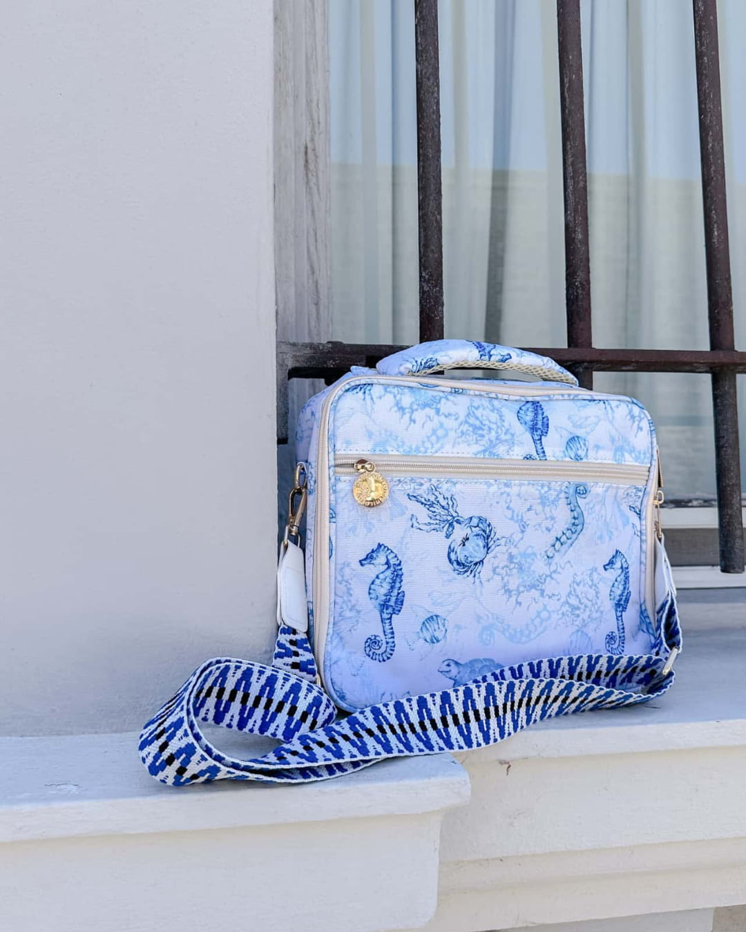 Insulated lunch bag with blue ocean print and detachable wide cross-body strap for hands-free adult or kids travel.