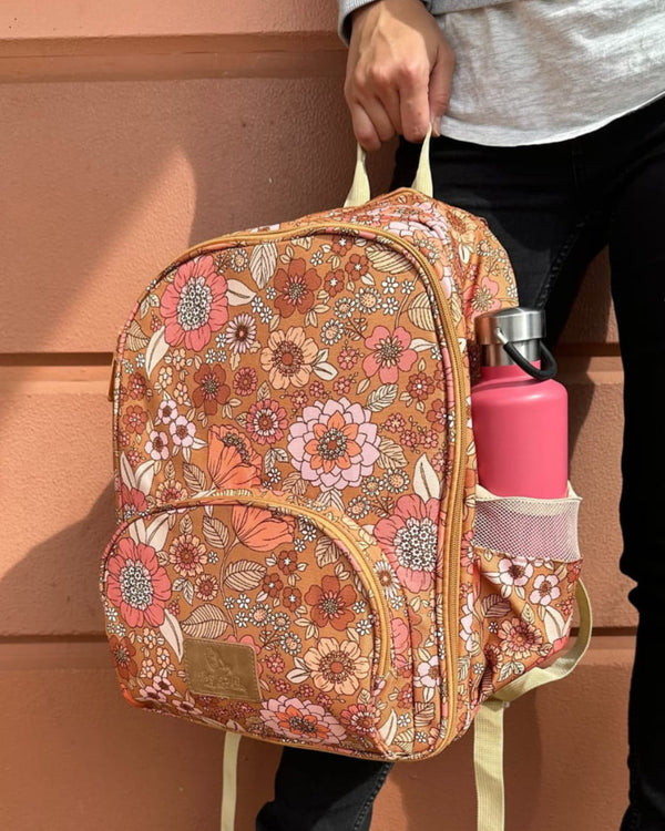 Woman holding retro floral print small backpack, showing full size, durable bottle pocket, and zipper compartments.