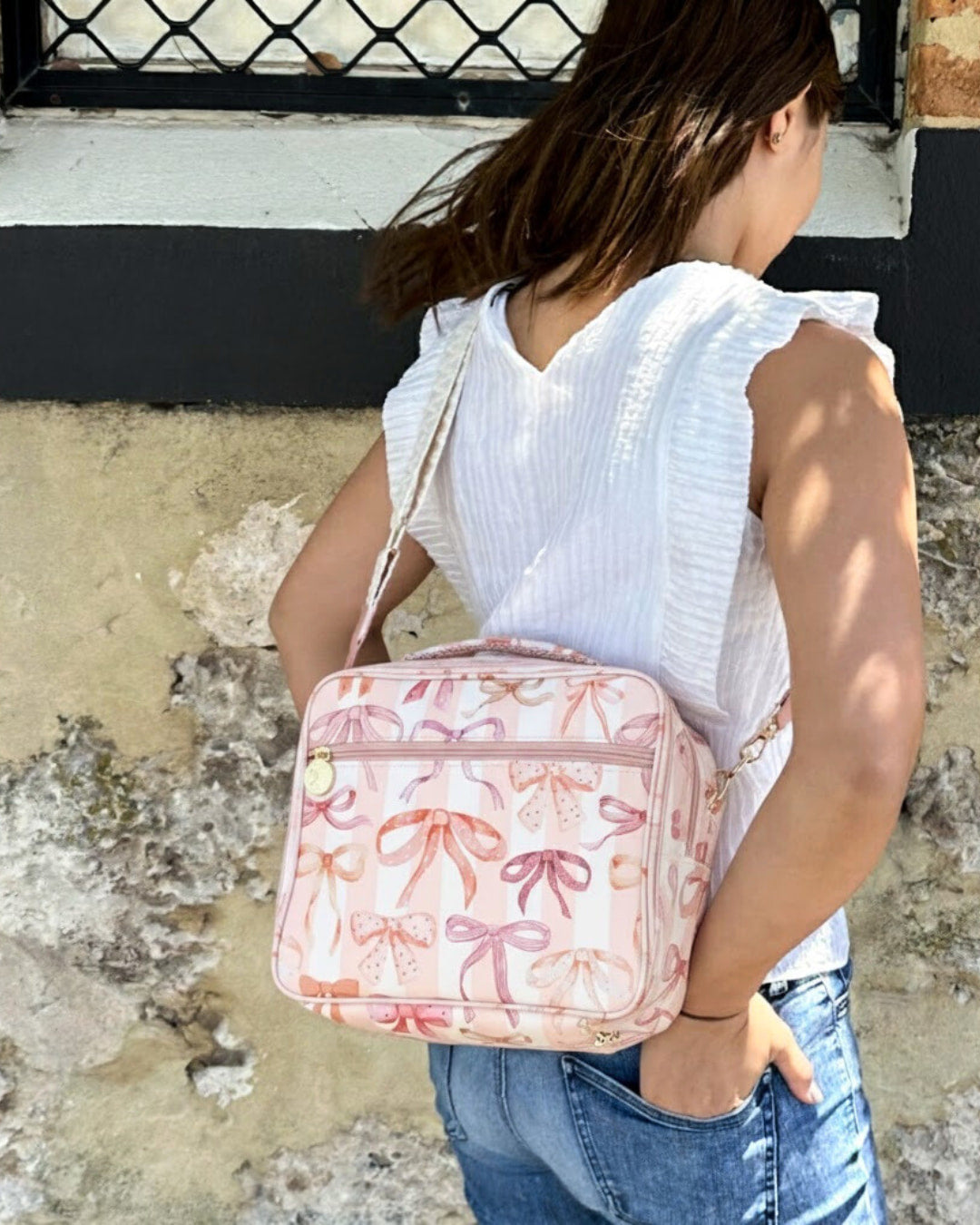 Woman wearing pink bow print insulated lunch bag with cross-body strap for stylish adult use, work, or travel.