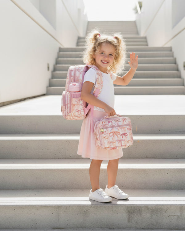 Young girl with a pink backpack and matching bag on concrete stairs
