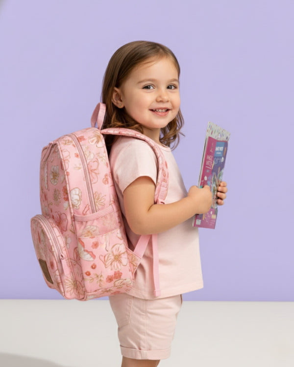 Young girl with a pink floral backpack and pink book against a light purple background