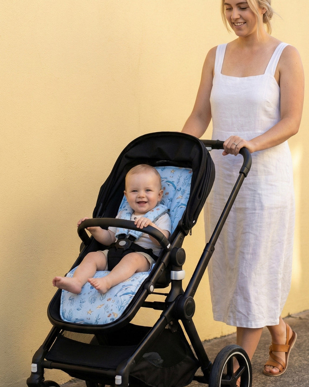 Woman pushing a stroller with a baby inside against a yellow background
