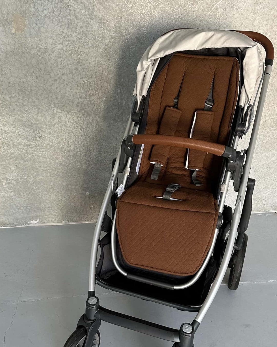 Empty stroller fitted with the reversible chocolate brown side of the pram liner, demonstrating alternate color option.