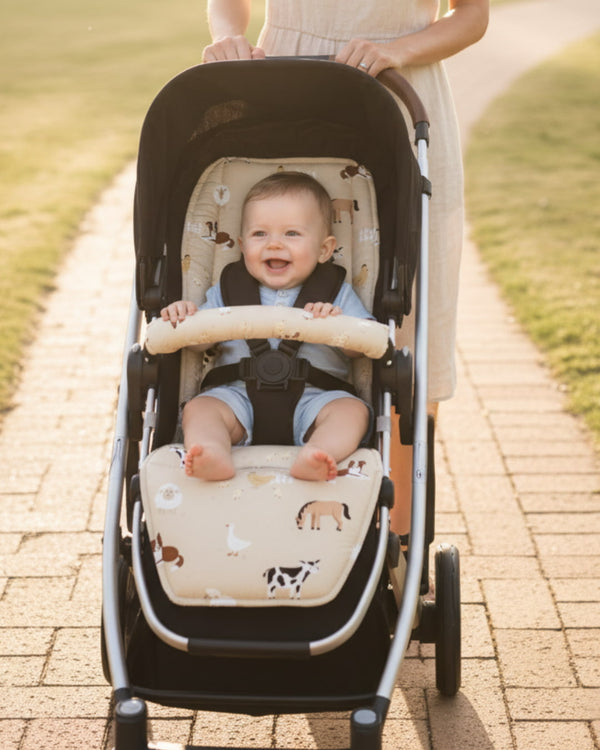Baby in a stroller with a patterned seat cover, walking on a paved path.