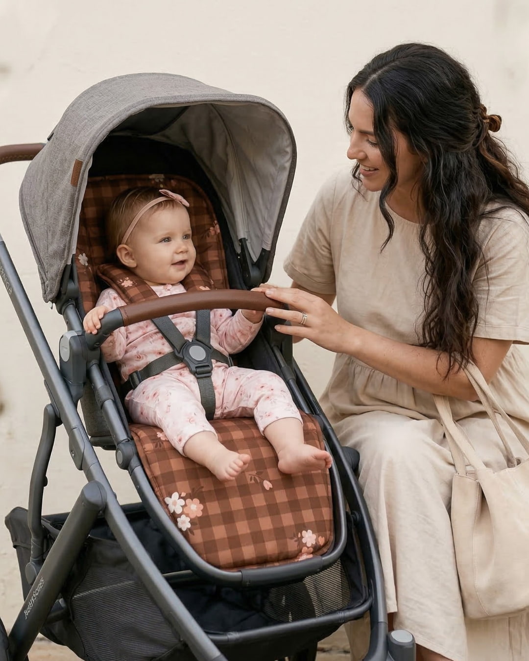Woman interacting with a baby in a stroller with a gingham floral patterned stroller liner. 