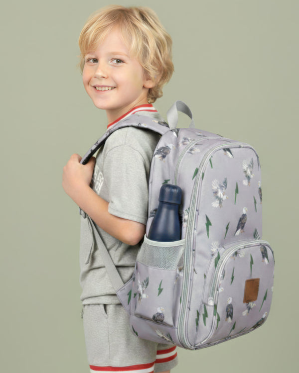 Child wearing a gray backpack with animal prints on a plain background