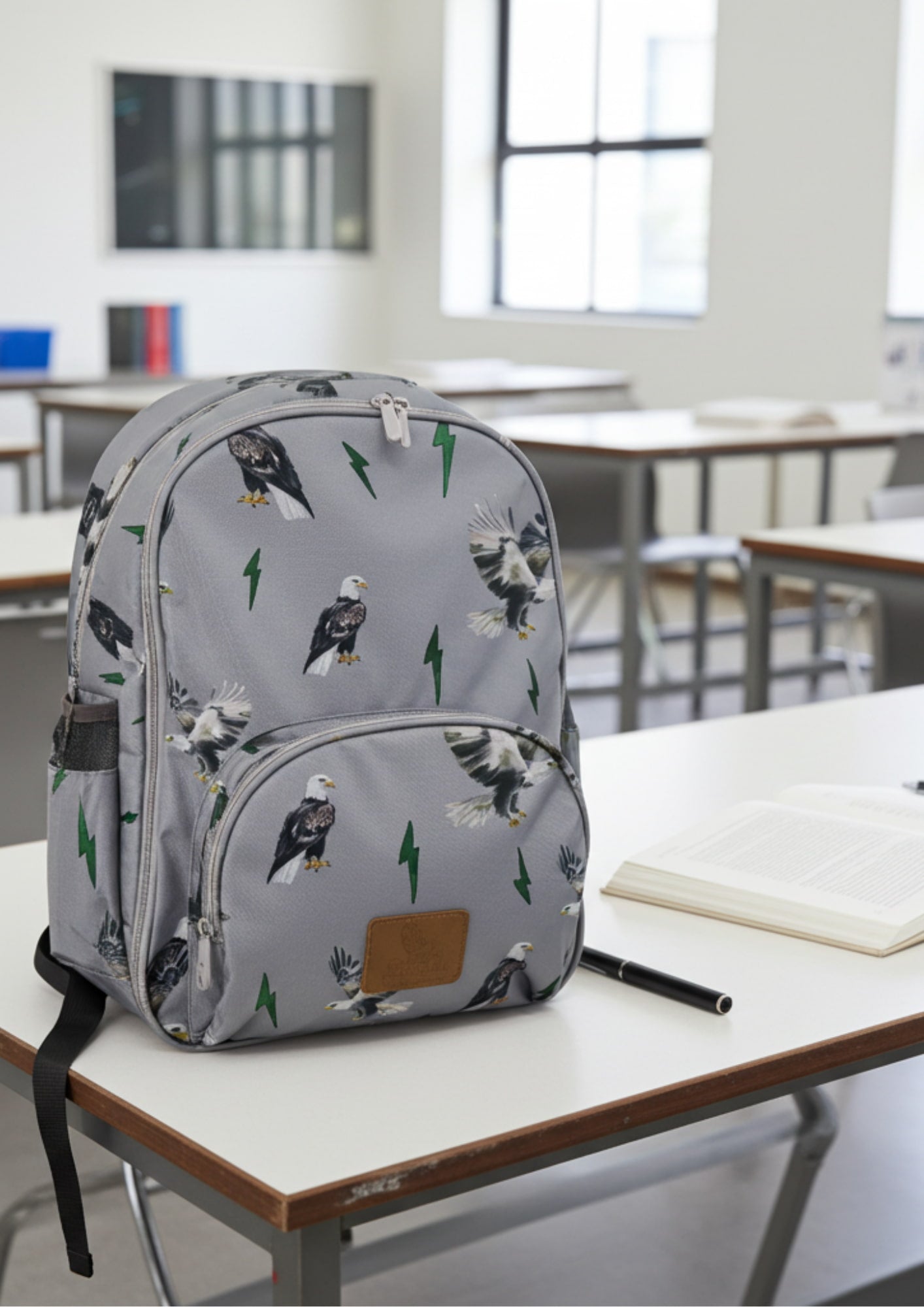 Gray backpack with eagle pattern on a classroom desk