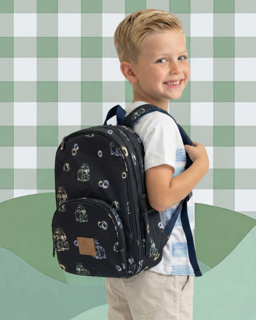 Child wearing a black backpack with a pattern against a green and white checkered background