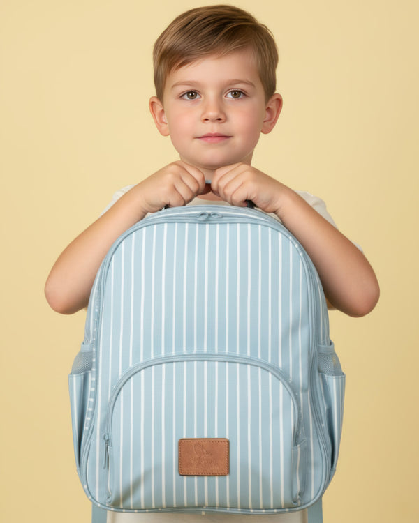 Child holding a light blue striped backpack against a beige background