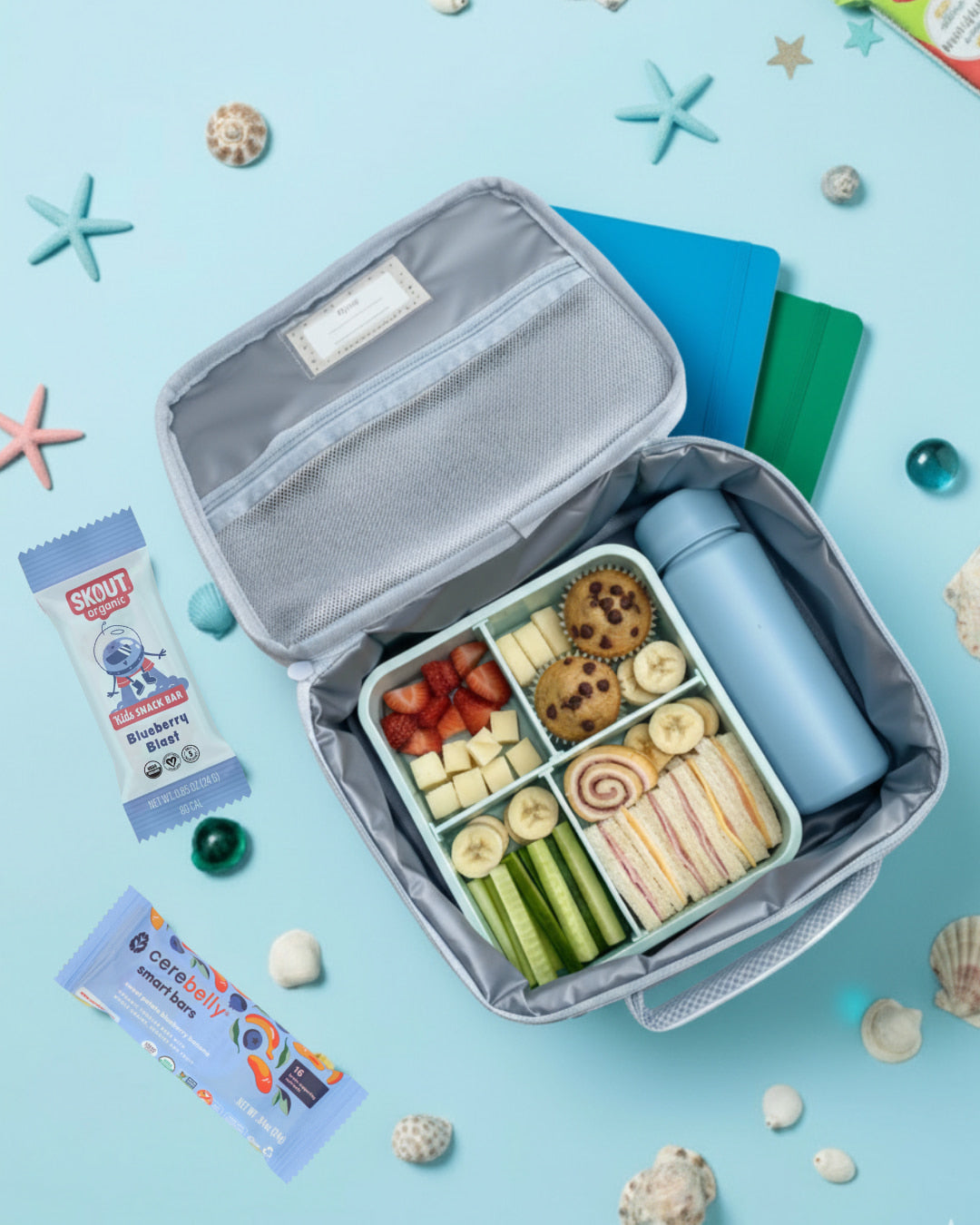Open lunchbox with snacks and a water bottle on a blue background with decorative elements.
