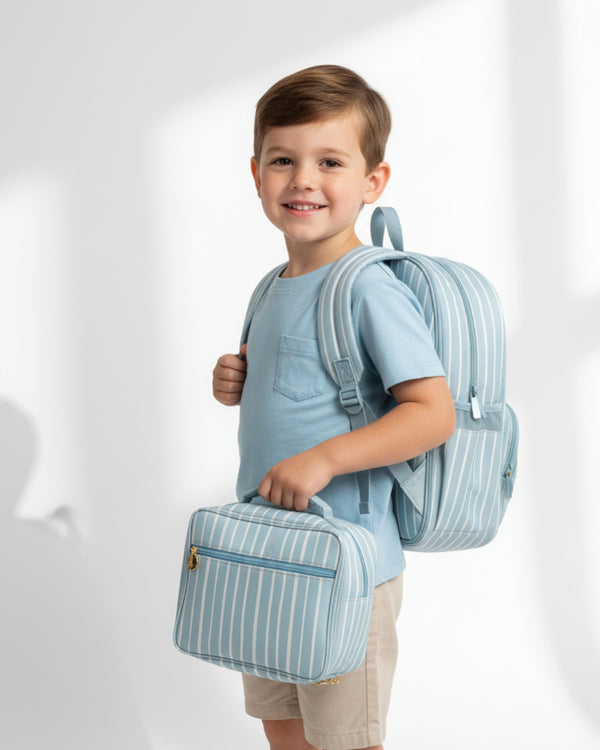 Child wearing a light blue backpack and holding a matching bag on a white background