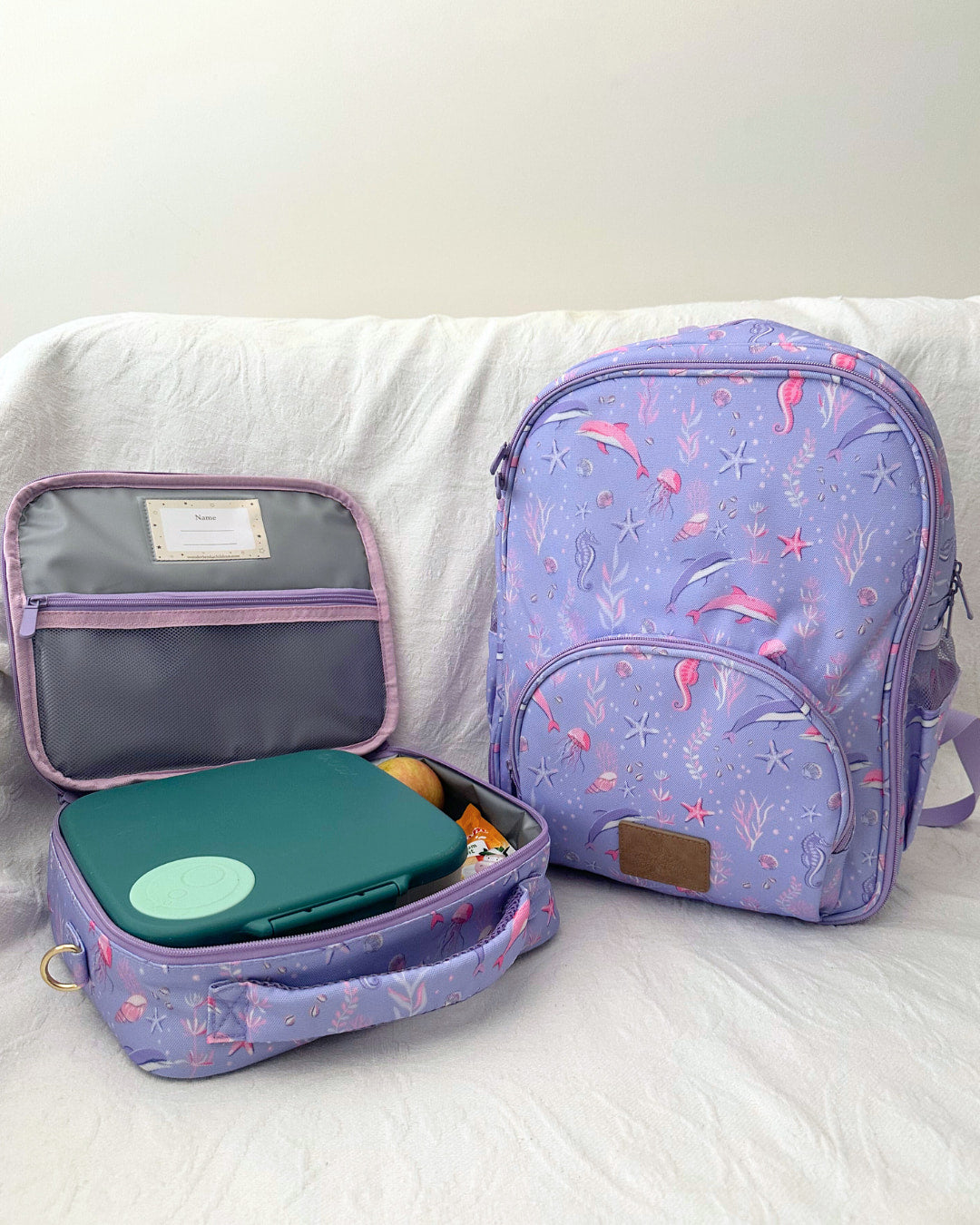 Purple backpack with a lunch box on a white surface