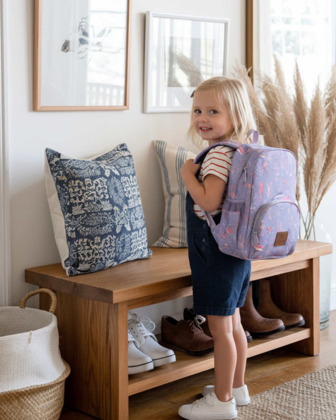 Child with a purple backpack standing on a wooden bench in a home setting.