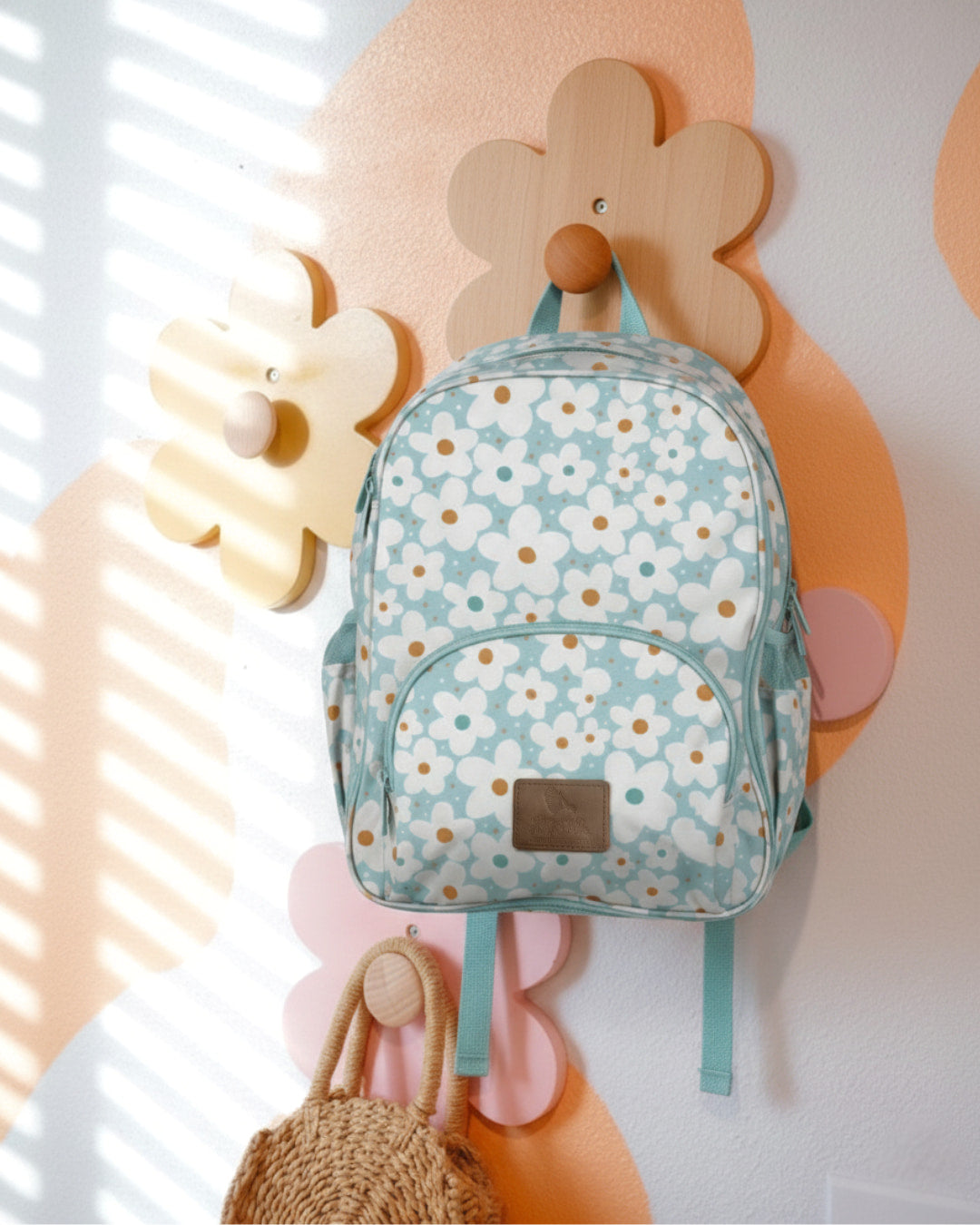 Floral-patterned backpack hanging on a decorative wall with pastel colors