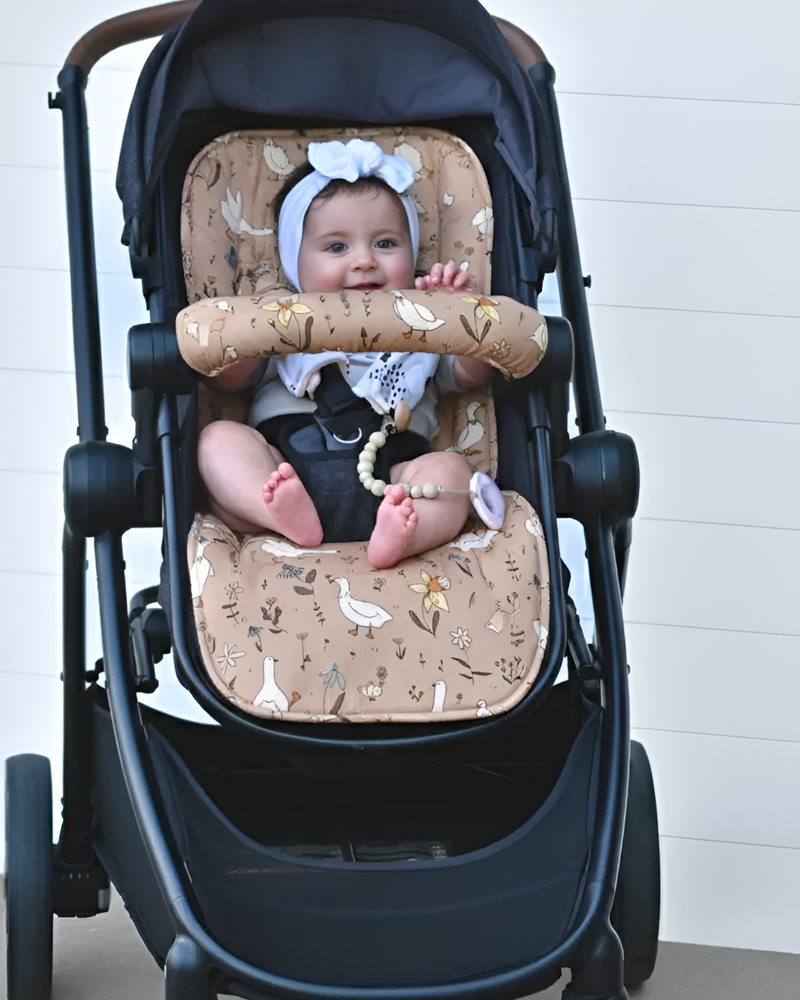 Baby in a stroller with a floral cushion on a white background