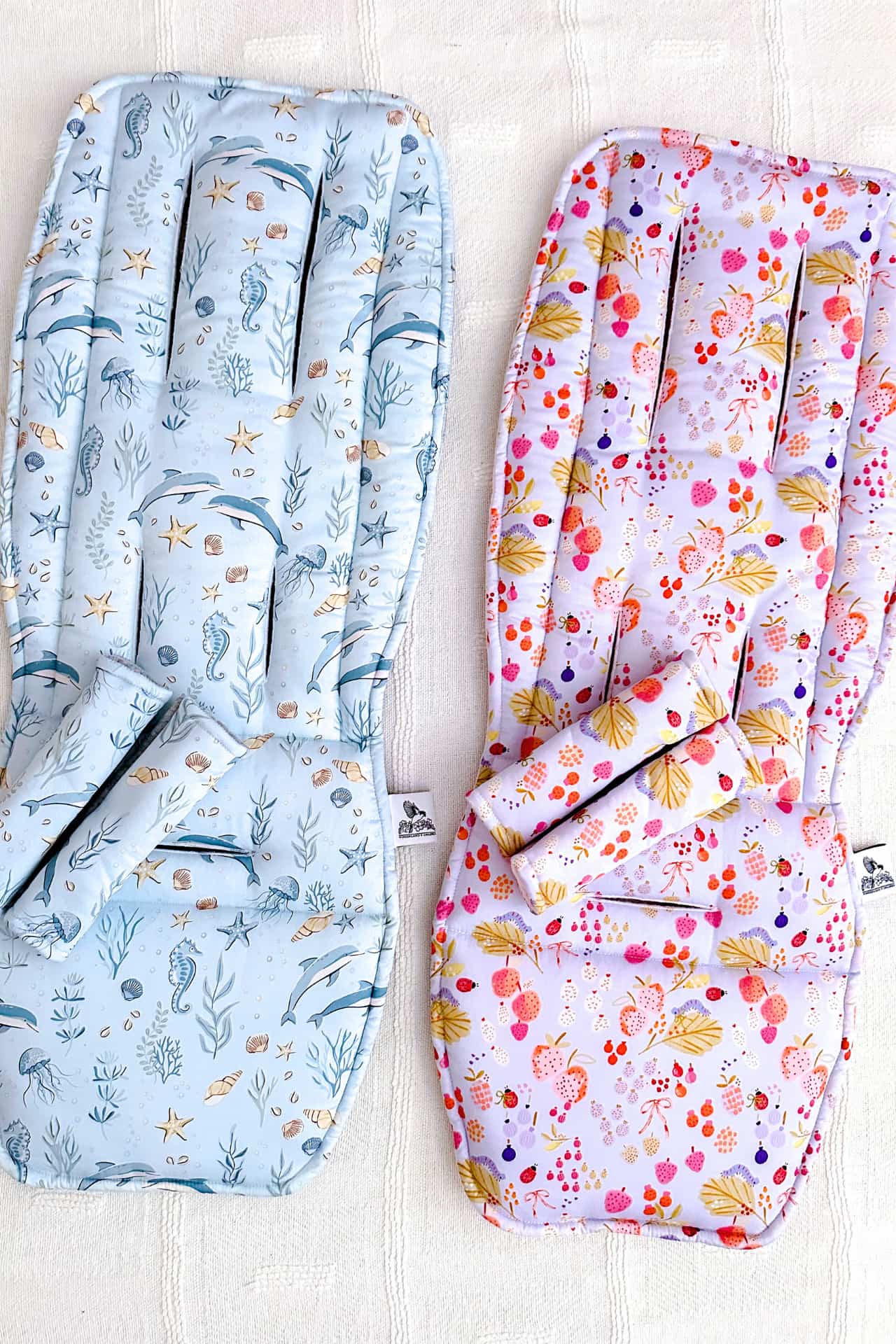 Two baby seat covers with ocean-themed and floral patterns 