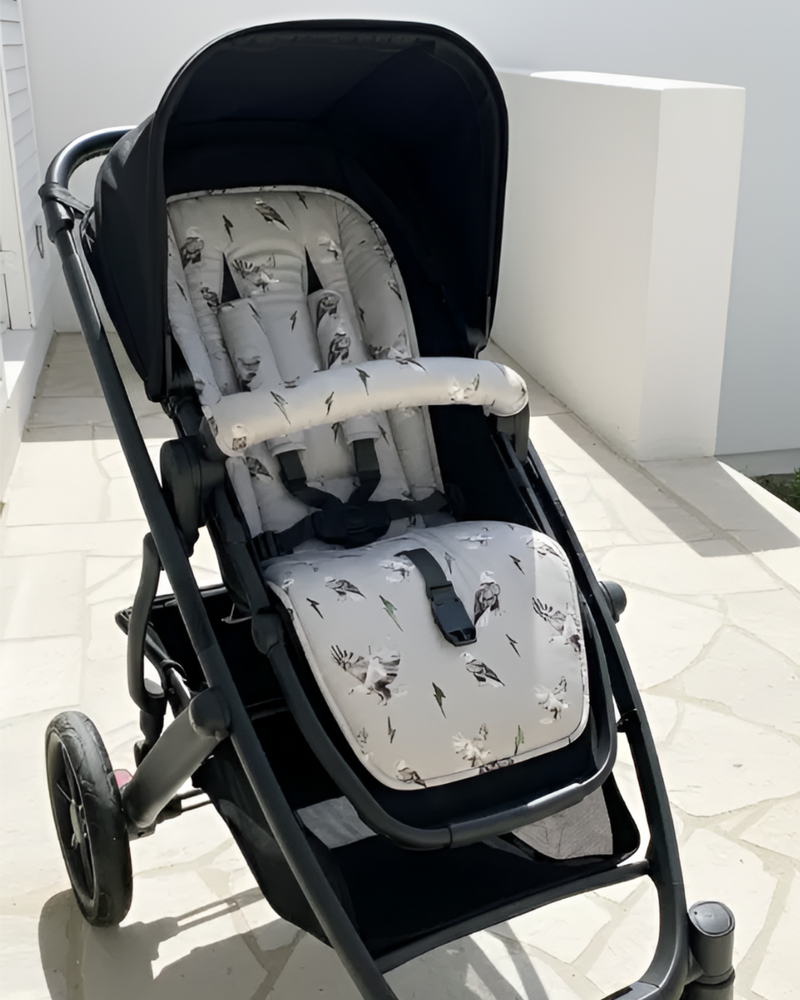 Black stroller with patterned seat and backrest on a tiled floor.