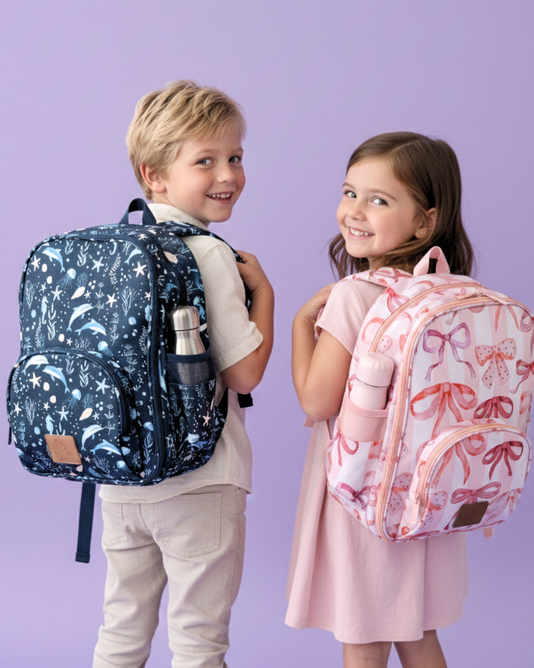 Two children with patterned backpacks on a purple background