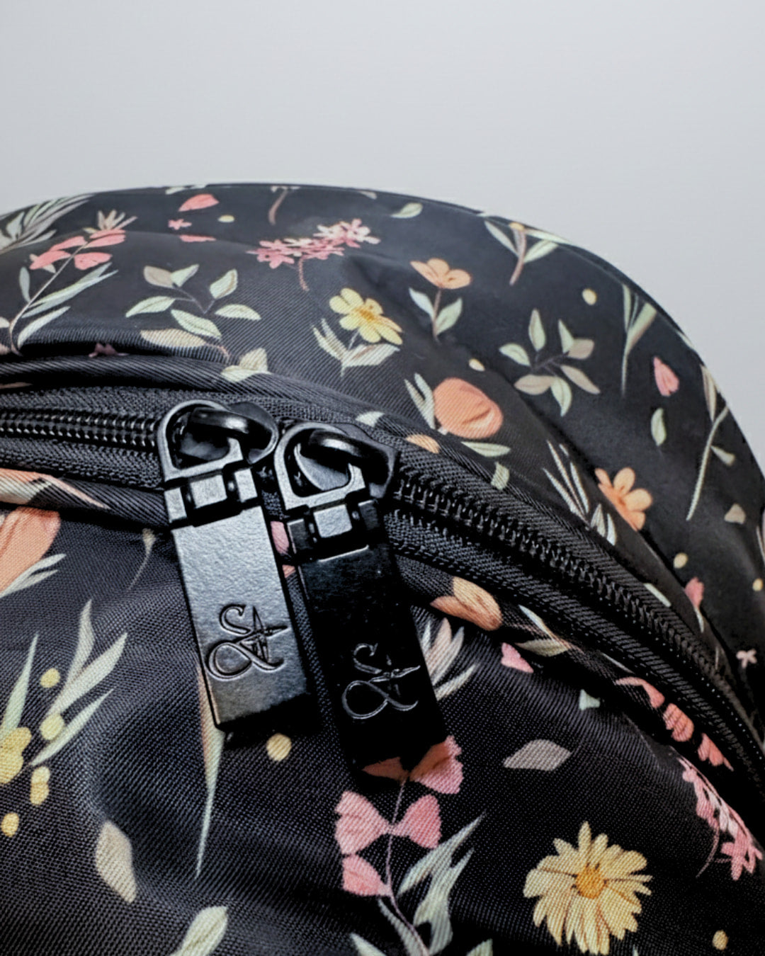Floral-patterned bag with a visible brand logo on a gray background