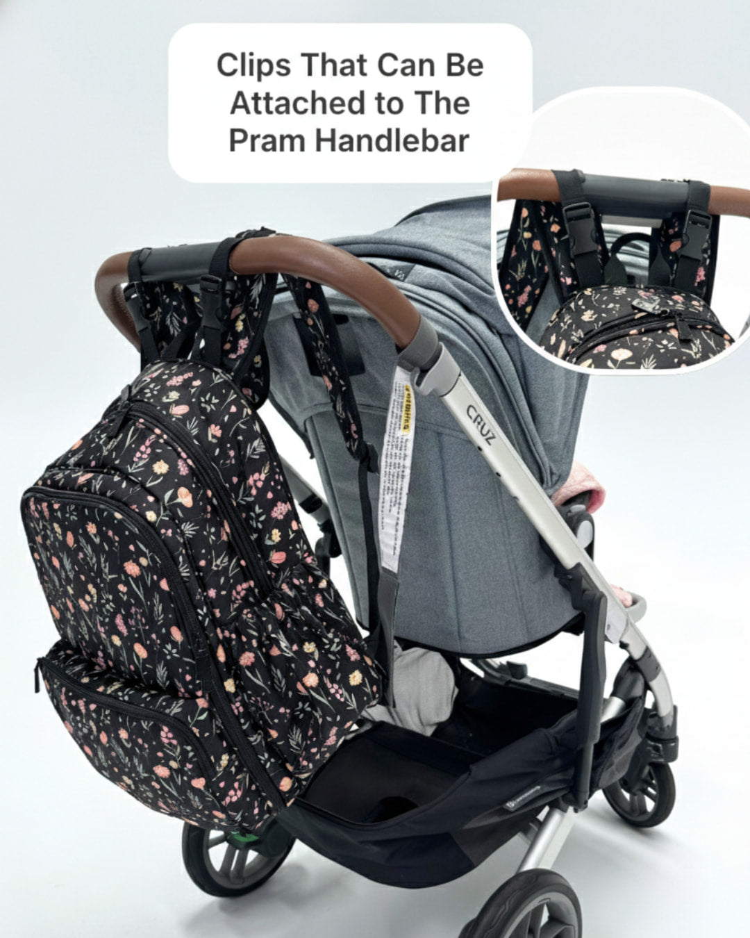 Baby stroller with a floral-patterned bag attached to the handlebar, on a light gray background.