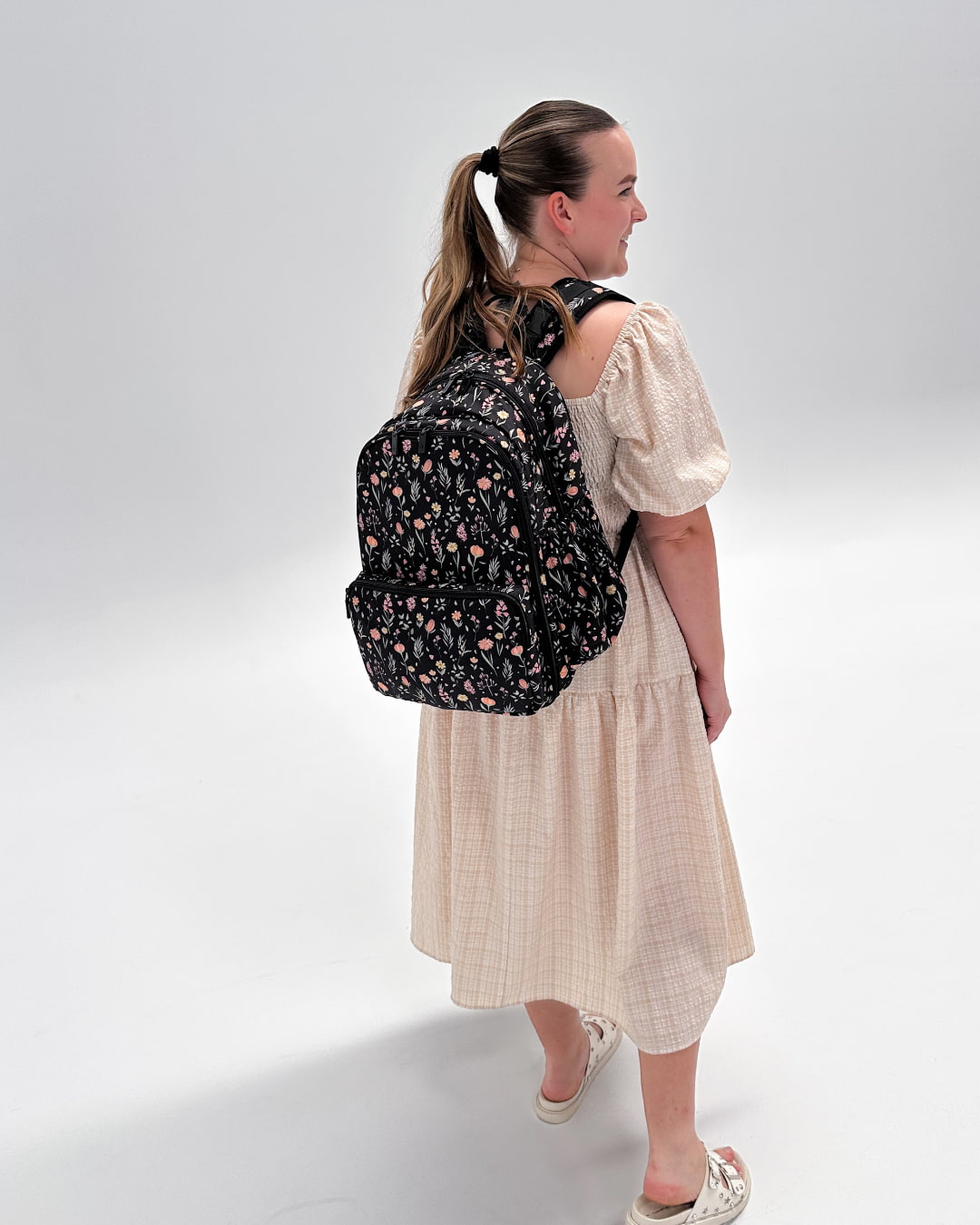Woman wearing a black floral backpack on a white background