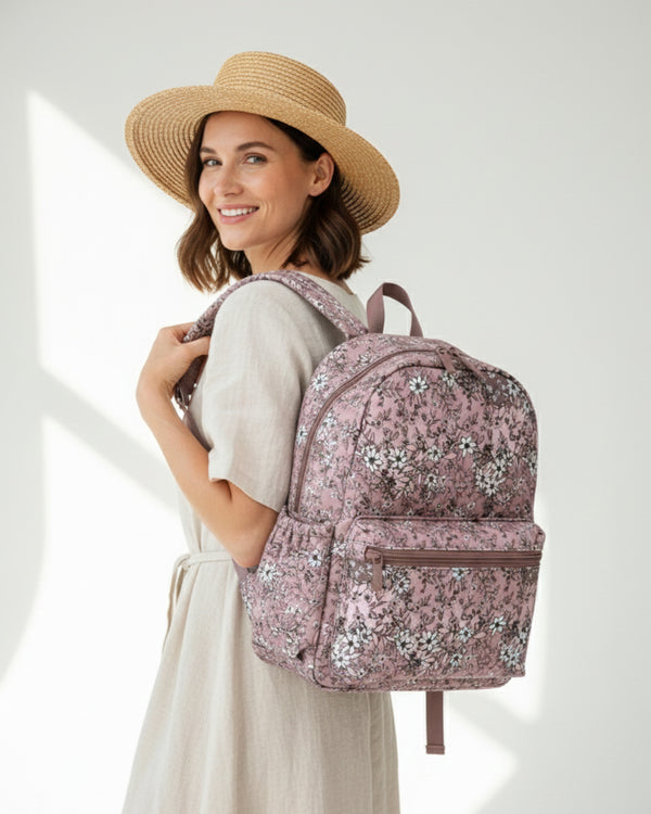 Woman wearing a floral backpack and straw hat on a white background