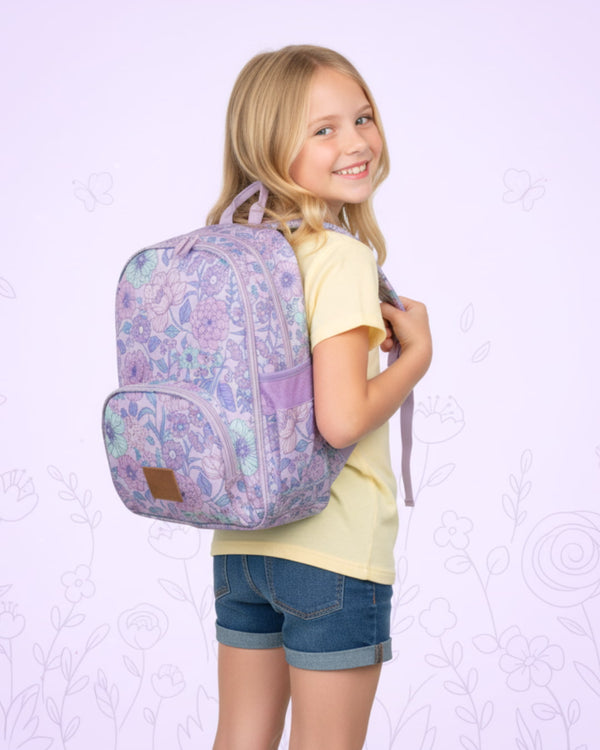 Young girl wearing a purple floral backpack against a light purple background