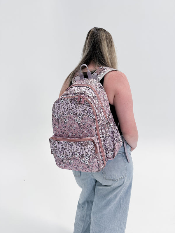 Person wearing a pink floral backpack on a white background