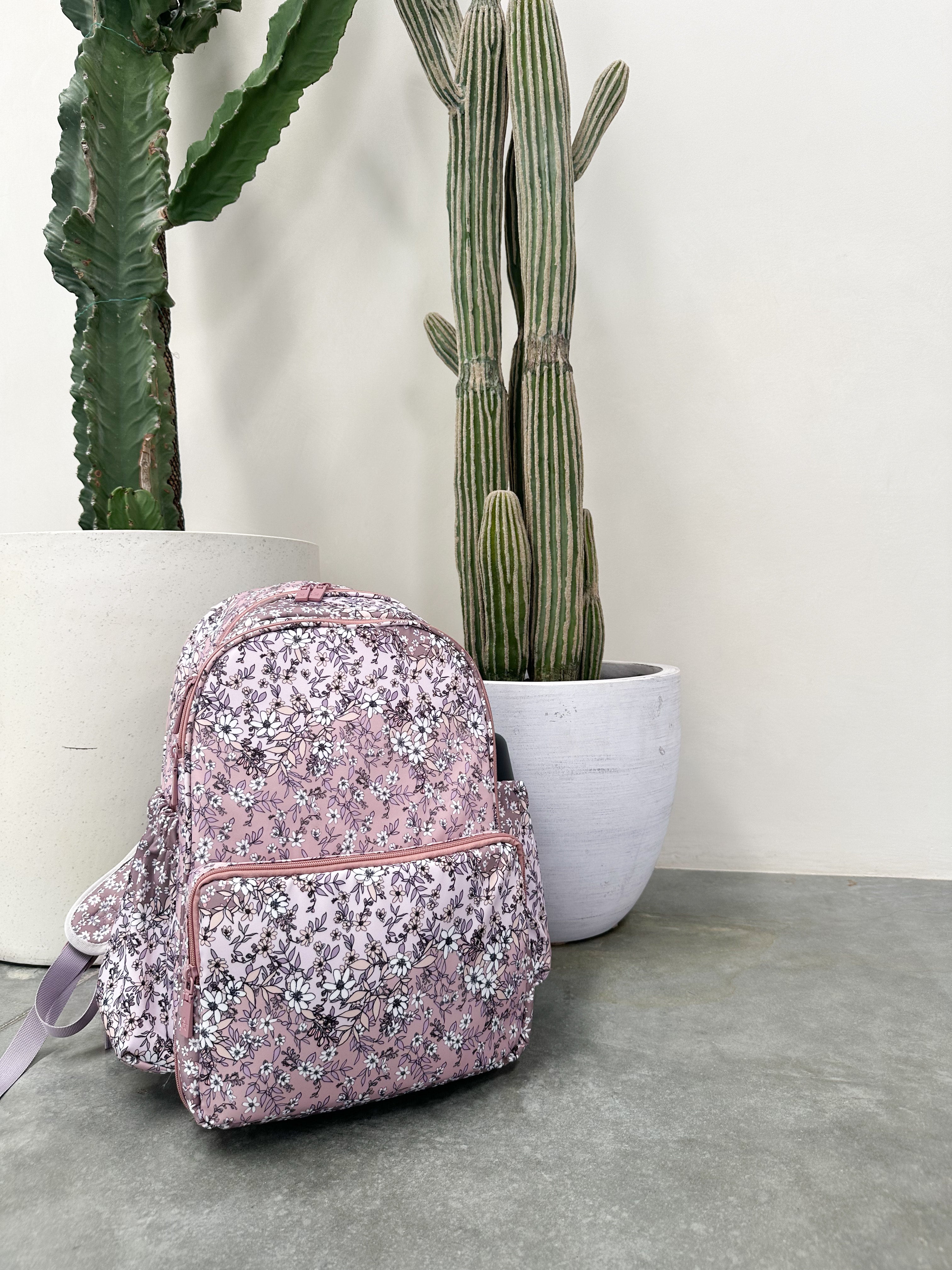 Pink sequin backpack on a concrete floor with cacti in the background
