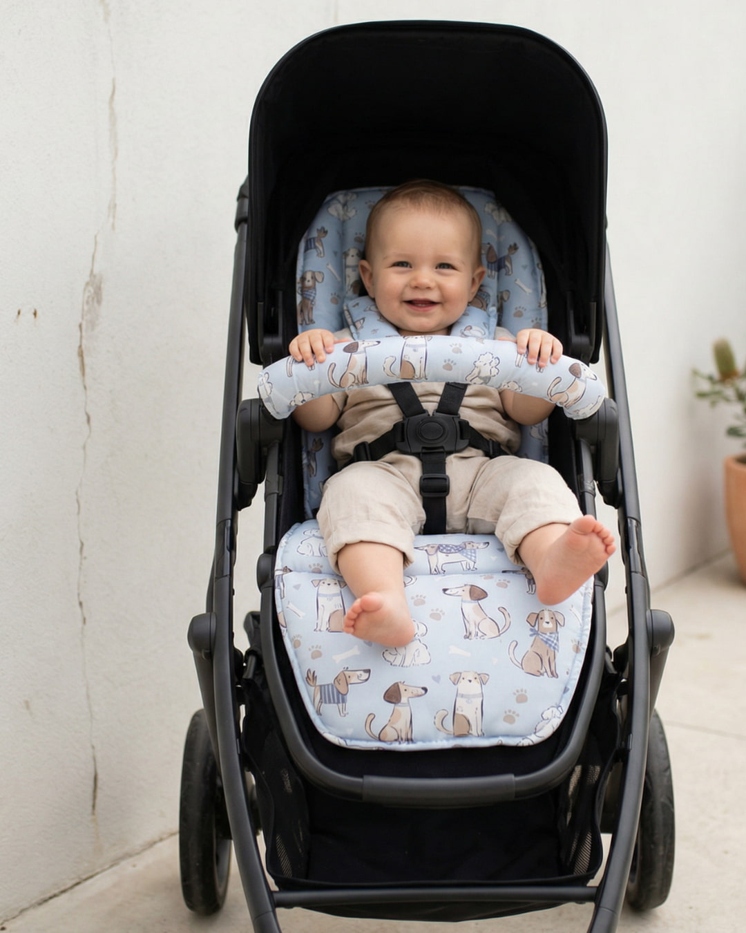 Baby sitting in a stroller with a dog patterned pram liner