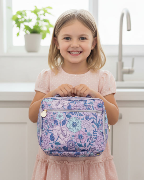 Young girl holding a floral-patterned lunch bag in a kitchen setting