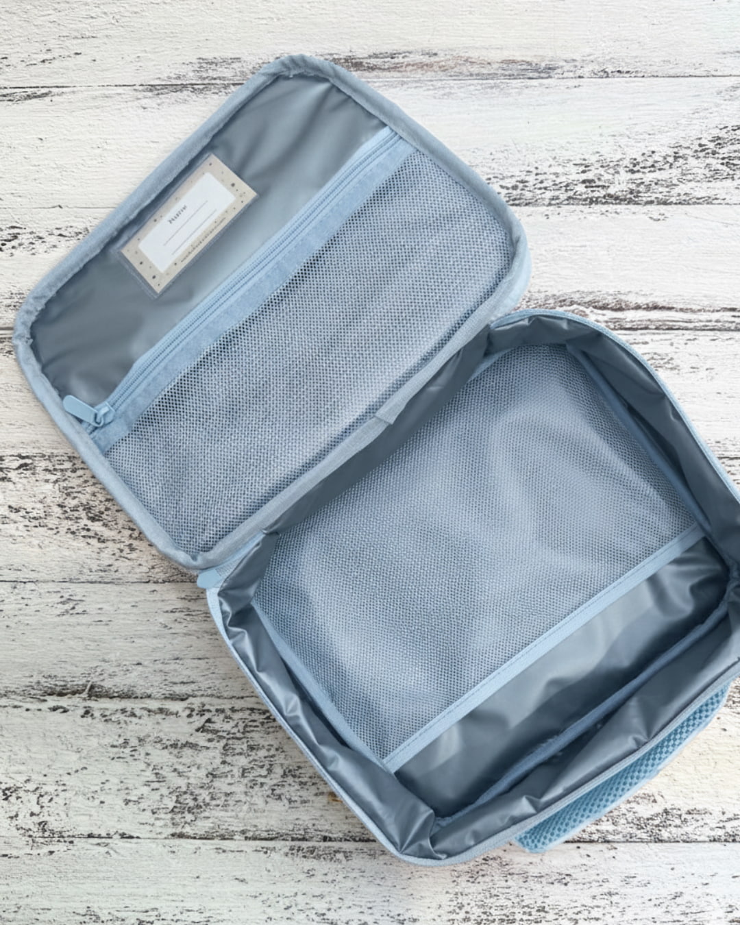 Blue travel organizer with mesh pockets on a wooden surface