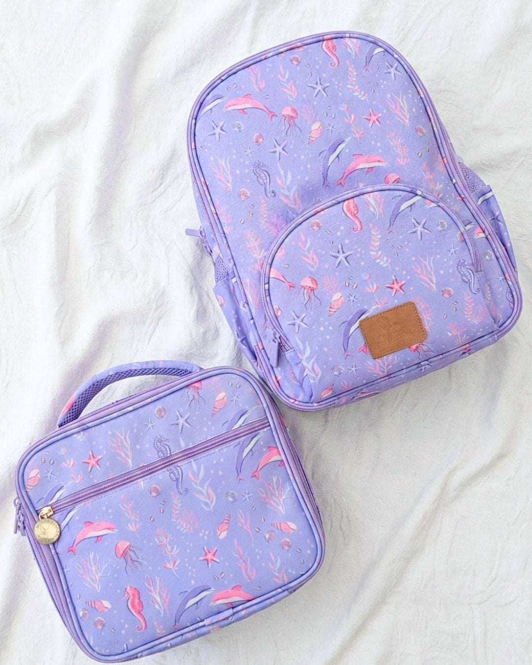 Two purple backpacks with mermaid pattern on a white background