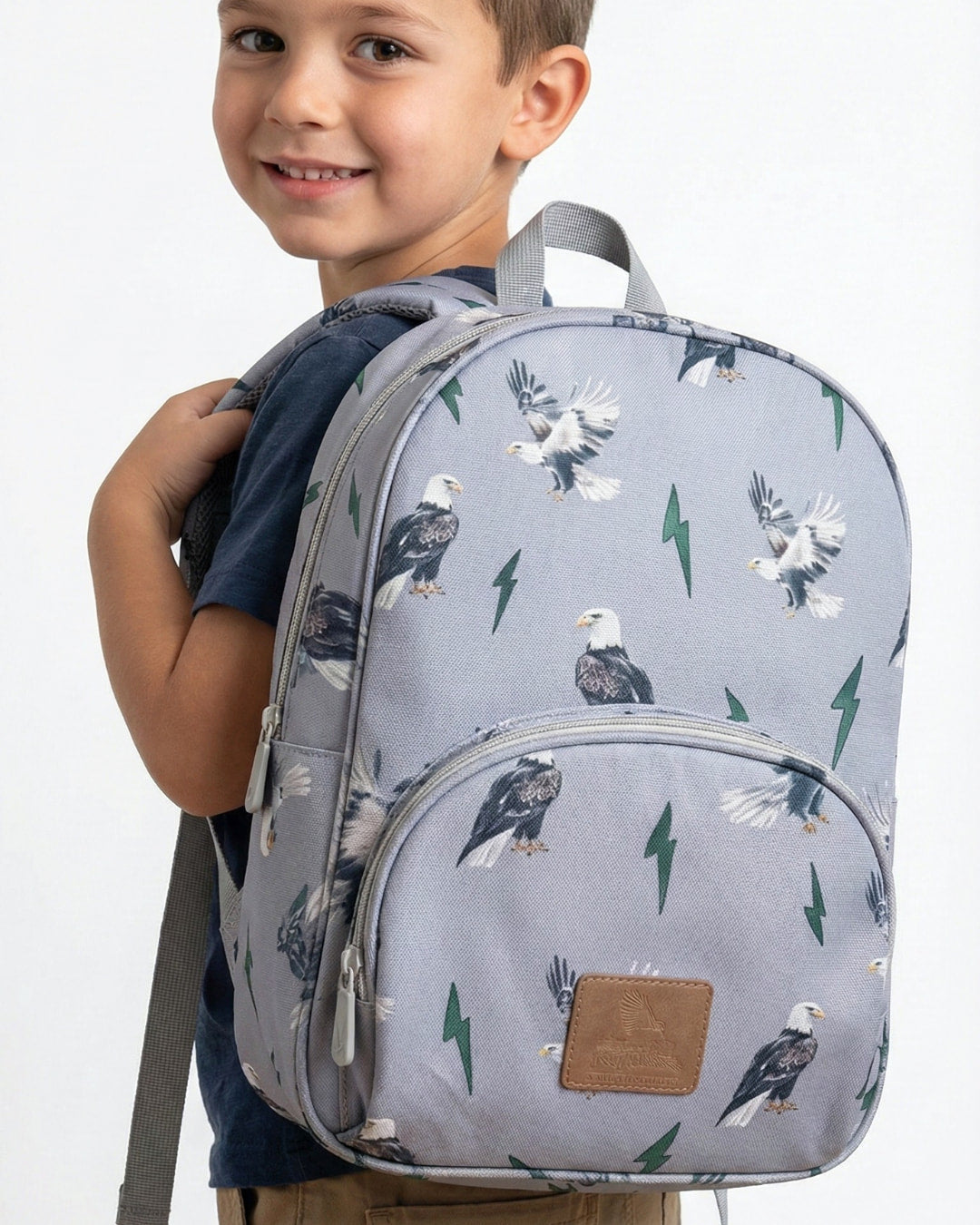 Child wearing a gray backpack with eagle designs on a white background