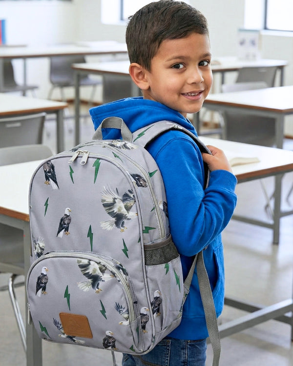 Child wearing a gray backpack with bird patterns in a classroom setting