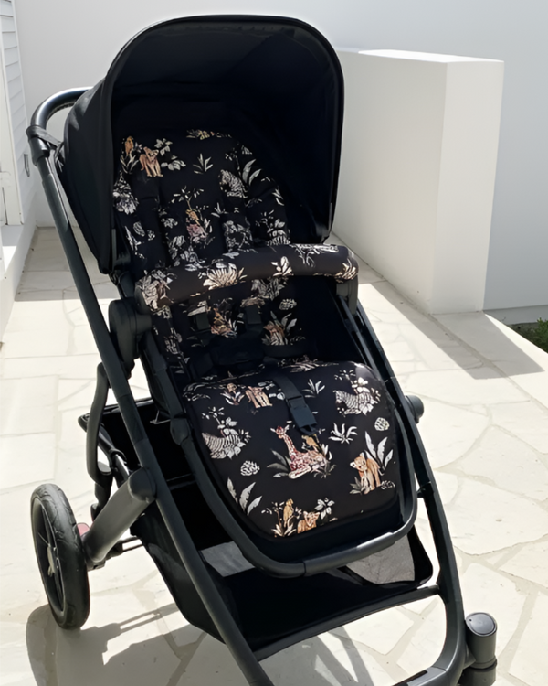 Empty stroller fitted with a black safari animal-print pram liner and matching padded bumper bar cover, displayed outdoors in sunlight.