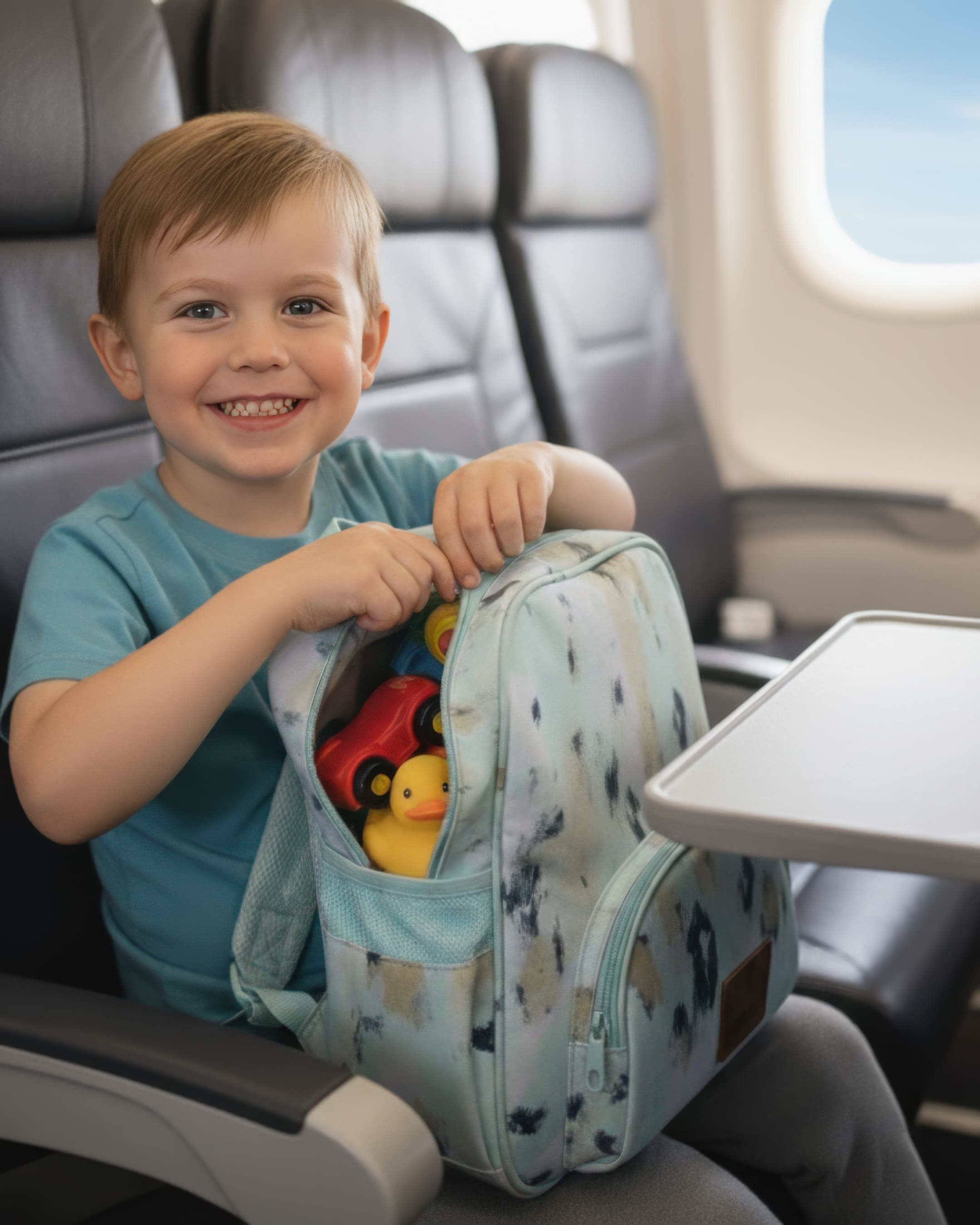 Child holding a toy bag with toys on an airplane