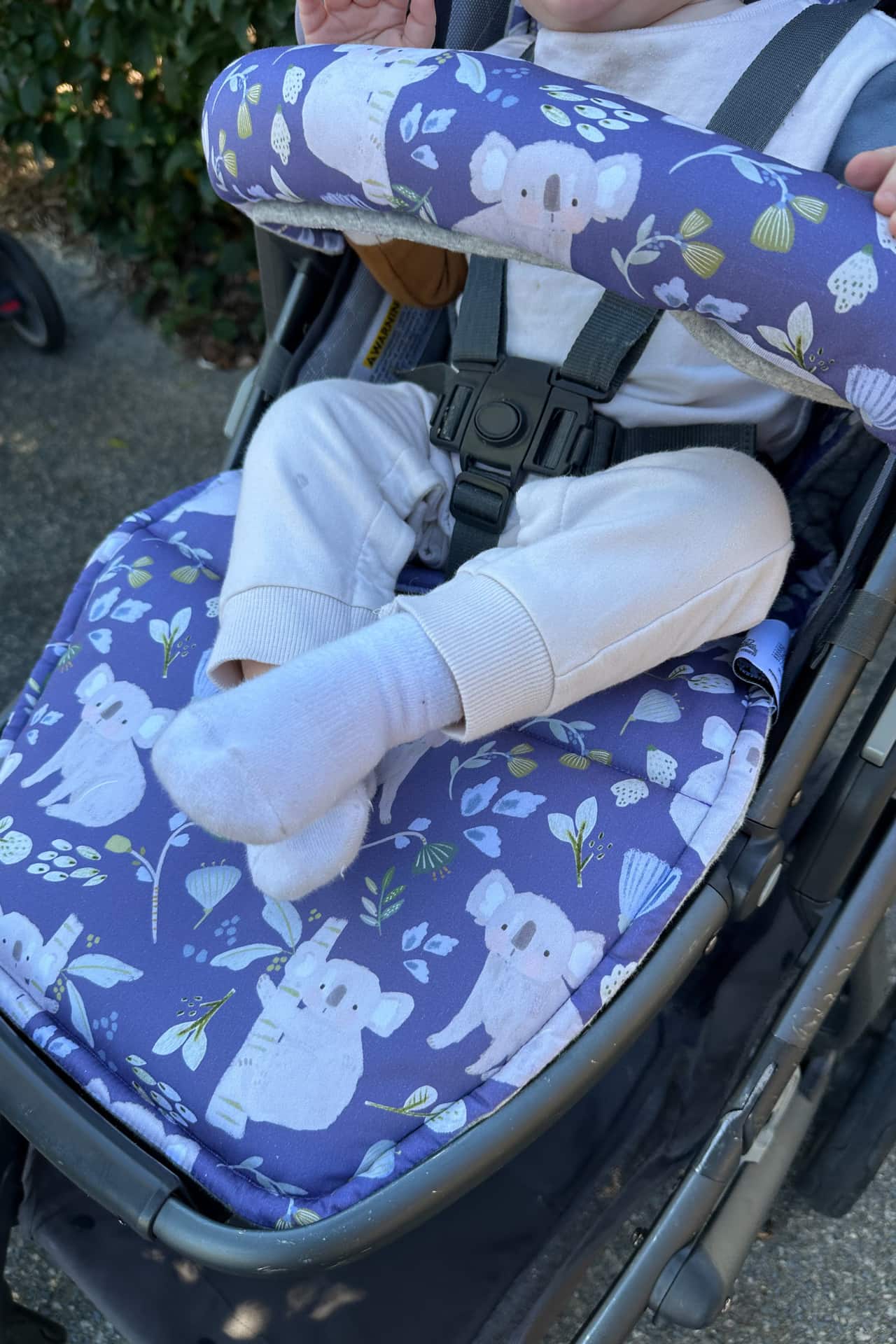 Child in a stroller with a blue navy seat cover featuring white animal designs.