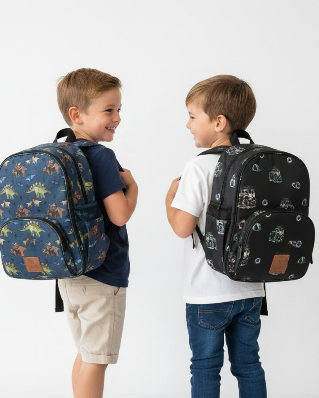 Two children wearing patterned backpacks on a plain background