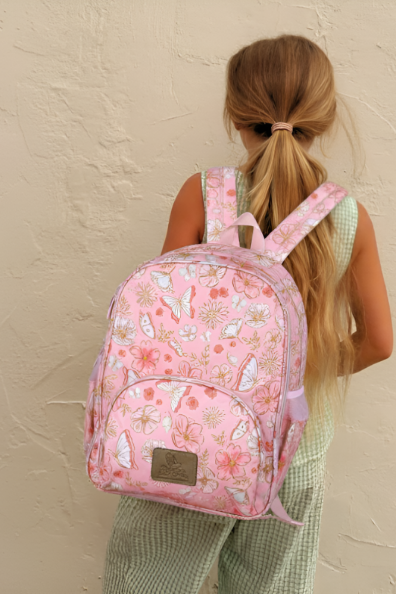 Person wearing a pink floral backpack against a beige wall