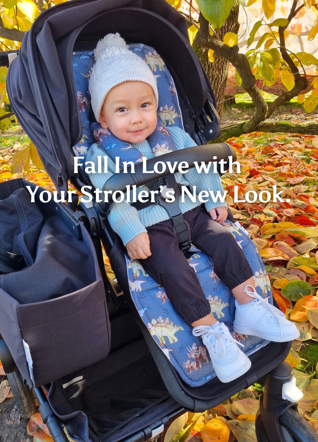 a toddler boy sitting on bugaboo donkey stroller with navy dinosaur pram liner