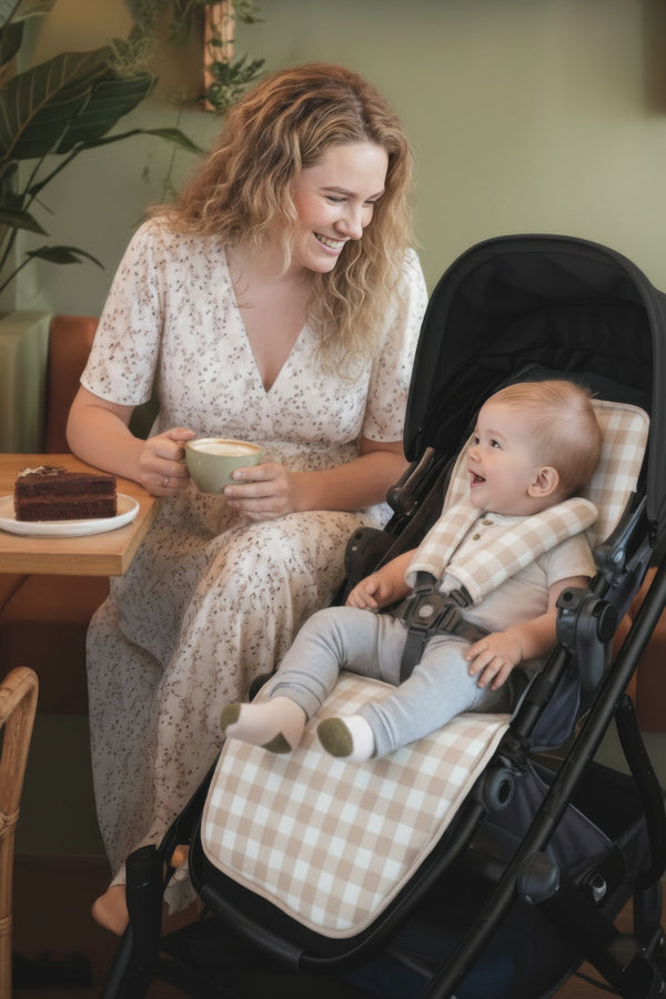 Woman with a baby in a stroller, both enjoying a treat indoors.
