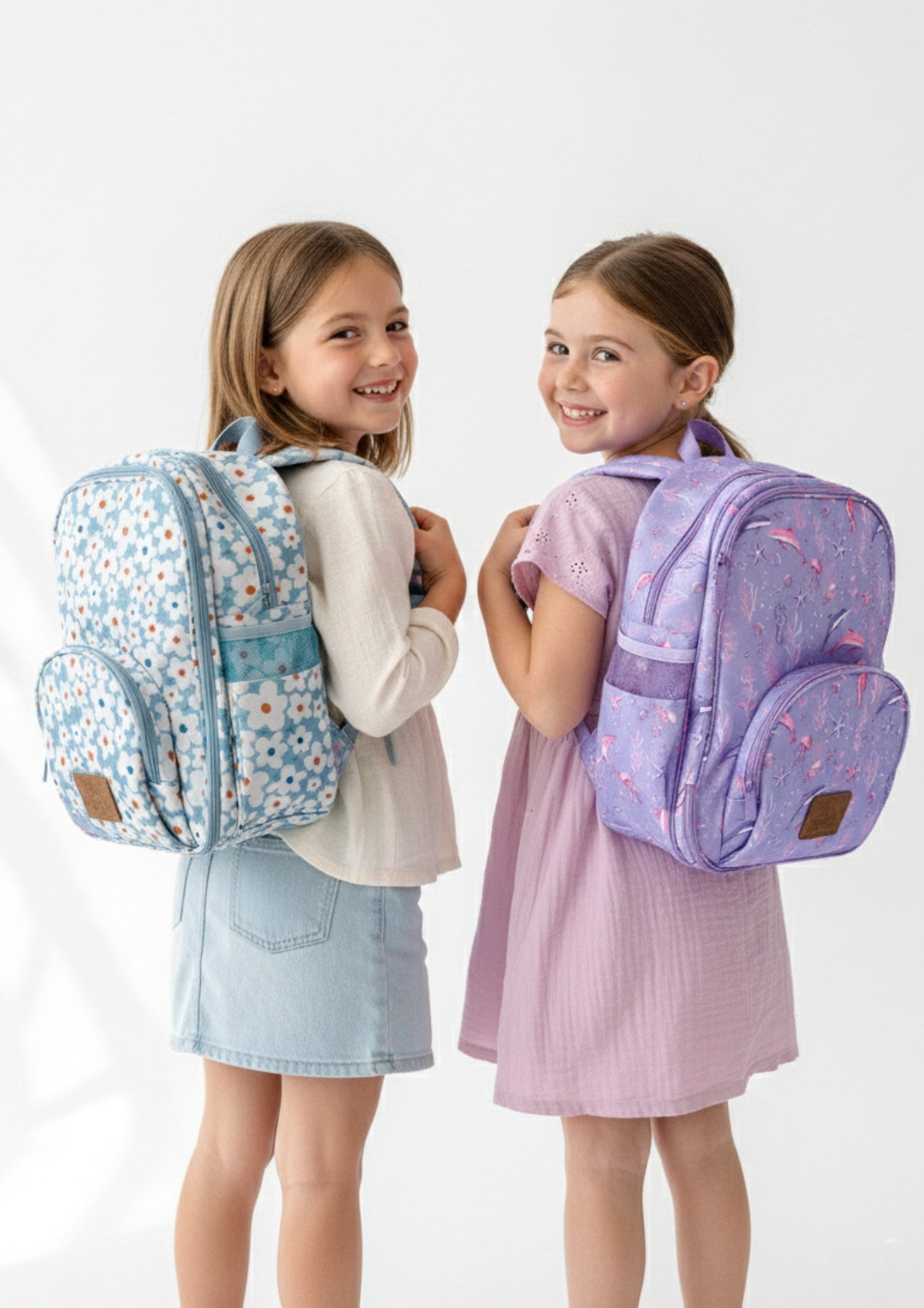 Two children wearing colorful backpacks on a white background